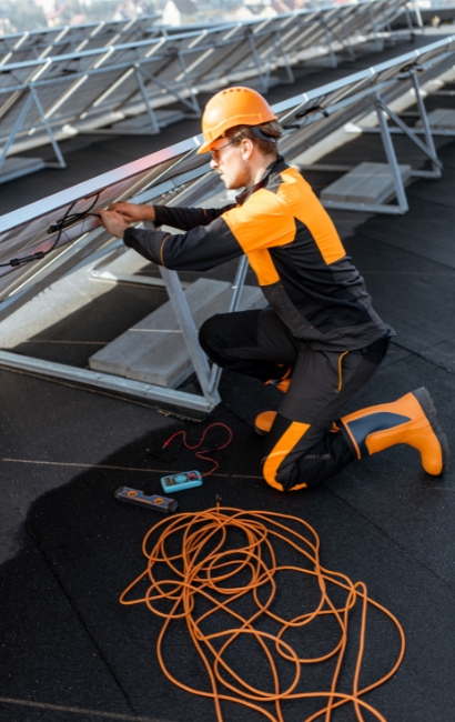 Técnico con casco realizando el mantenimiento de placas solares en vitoria-gasteiz en cubierta plana con estructuras inclinadas; revisión e inspección en Vitoria-Gasteiz, Álava, País Vasco