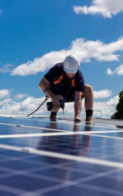 Técnico con casco instalando paneles solares con taladro en tejado; instalación fotovoltaica de autoconsumo en Vitoria-Gasteiz, Álava, País Vasco
